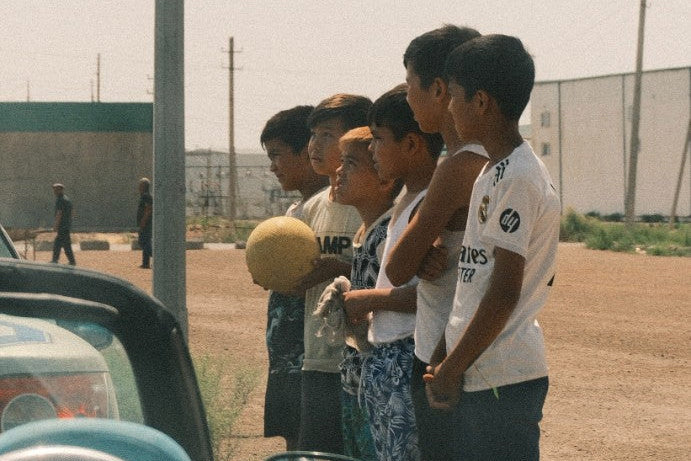 Children with a worn football watching the rally cars along the Silk Road