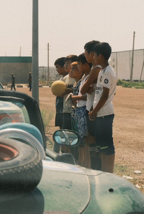Children with a worn football watching the rally cars along the Silk Road