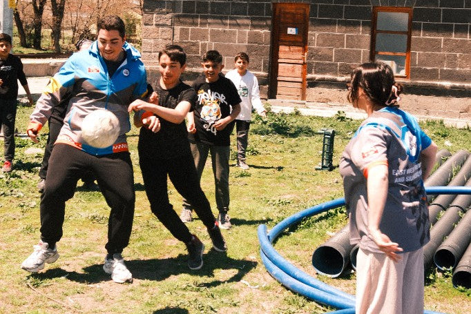 Kids and the rally team playing football together